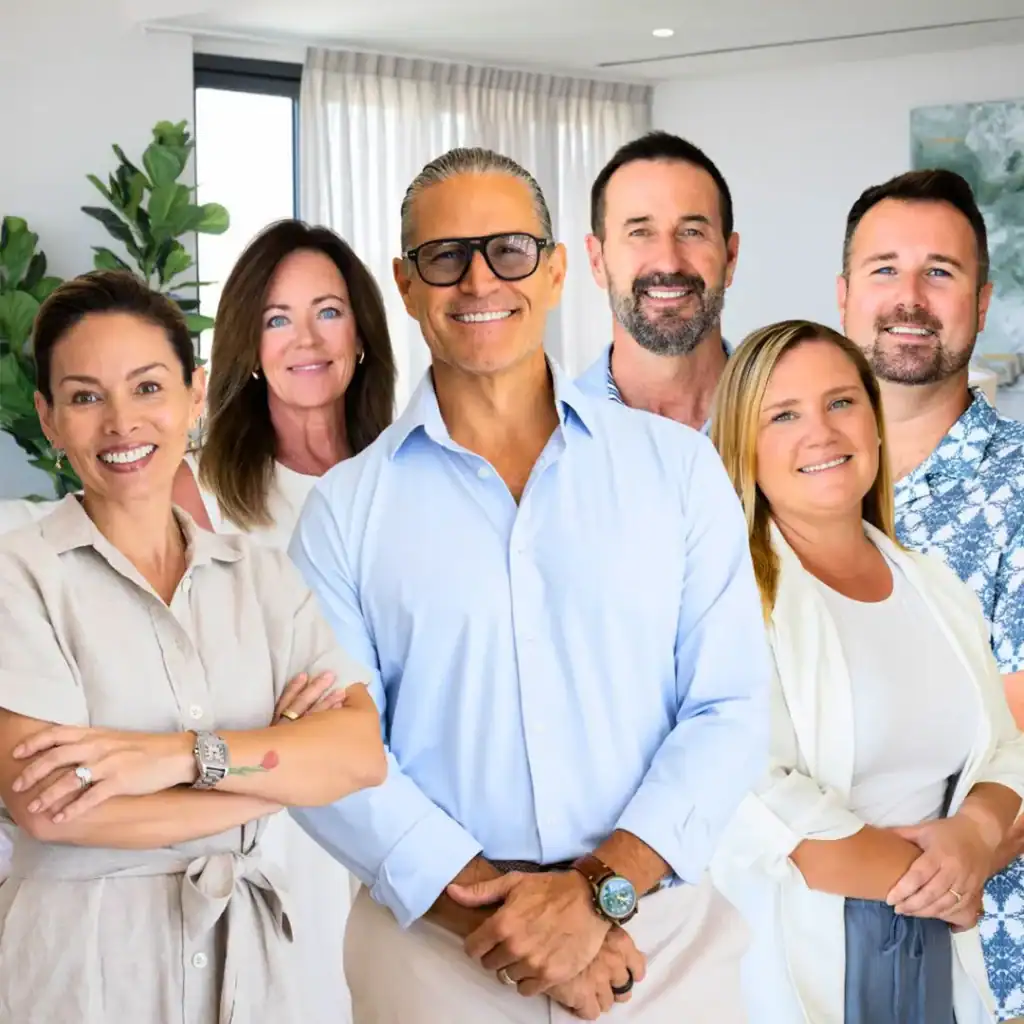 Six members of the Berkshire Hathaway HomeServices Baja Real Estate team standing together in a bright modern living room