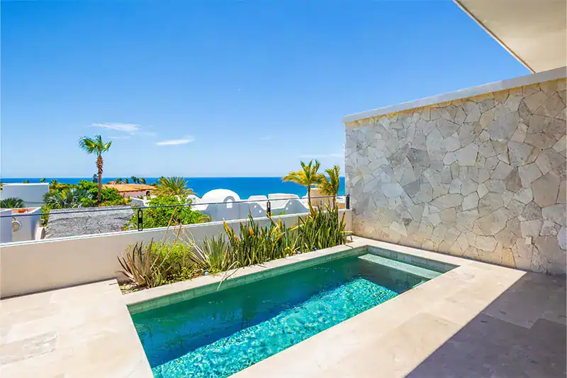 Private plunge pool on a stone-walled terrace with ocean views and desert palms