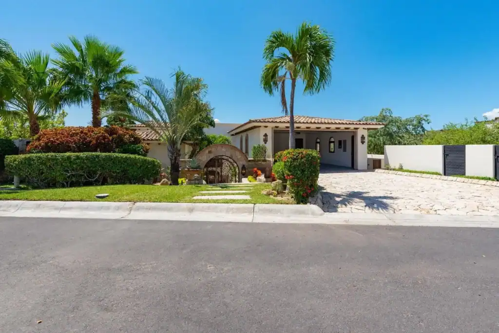 Luxury single-family home in Cabo del Sol with Mediterranean architecture, palm trees, and stone driveway