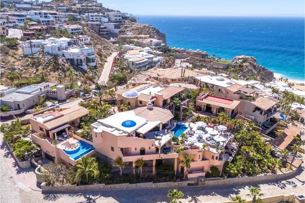 Mediterranean-style estates in Pedregal featuring terracotta tile roofs, domed architectural details, private pools, multi-level terraces, and Pacific Ocean views along the cobblestone hillside streets
