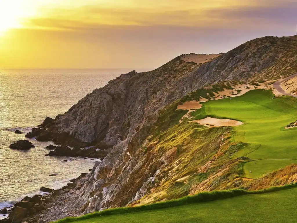 Sunset view of Quivira Golf Club's clifftop green perched on granite cliffs above the Pacific Ocean, with golden light reflecting on the water and dramatic coastal dunes