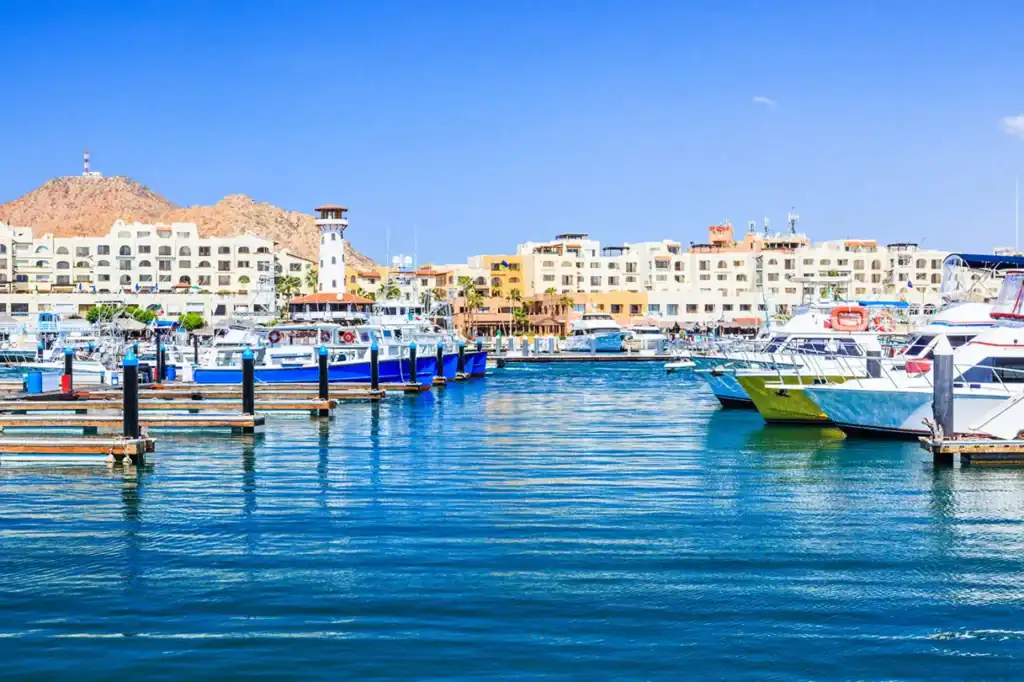 Sport fishing boats and yachts docked at Cabo San Lucas marina with waterfront hotels and Pedregal mountain in the background, Baja California Sur, Mexico.