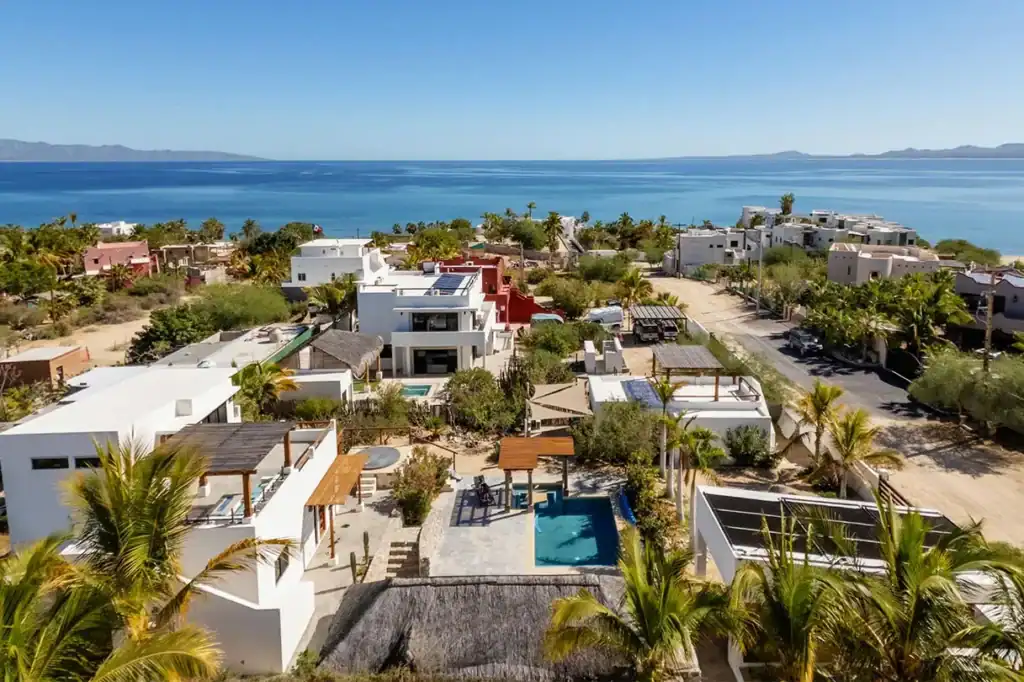 Aerial view of modern white residential homes with pools and solar panels in a low-density coastal community overlooking the Sea of Cortez and Isla Cerralvo, El Sargento, Baja California Sur, Mexico.
