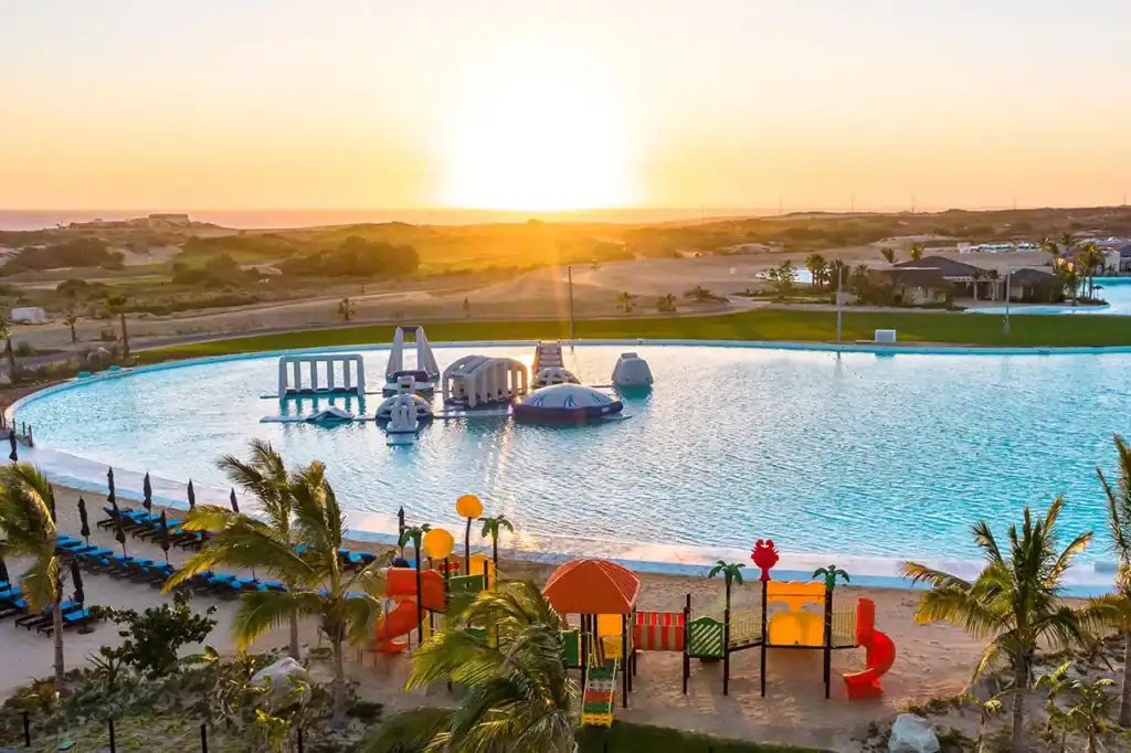 Crystal Lagoon amenity with water park, beach loungers, and children's playground at sunset in a gated Pacific side community, Los Cabos, Baja California Sur, Mexico.