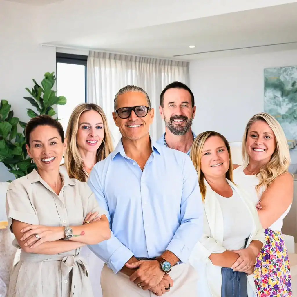Six members of the Berkshire Hathaway HomeServices Baja Real Estate team standing together in a bright modern living room