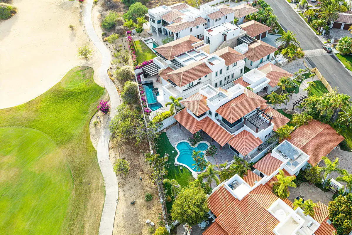 Aerial view of golf course homes in Los Cabos with tile roofs and private pools, comparing beachfront, golf or ocean view