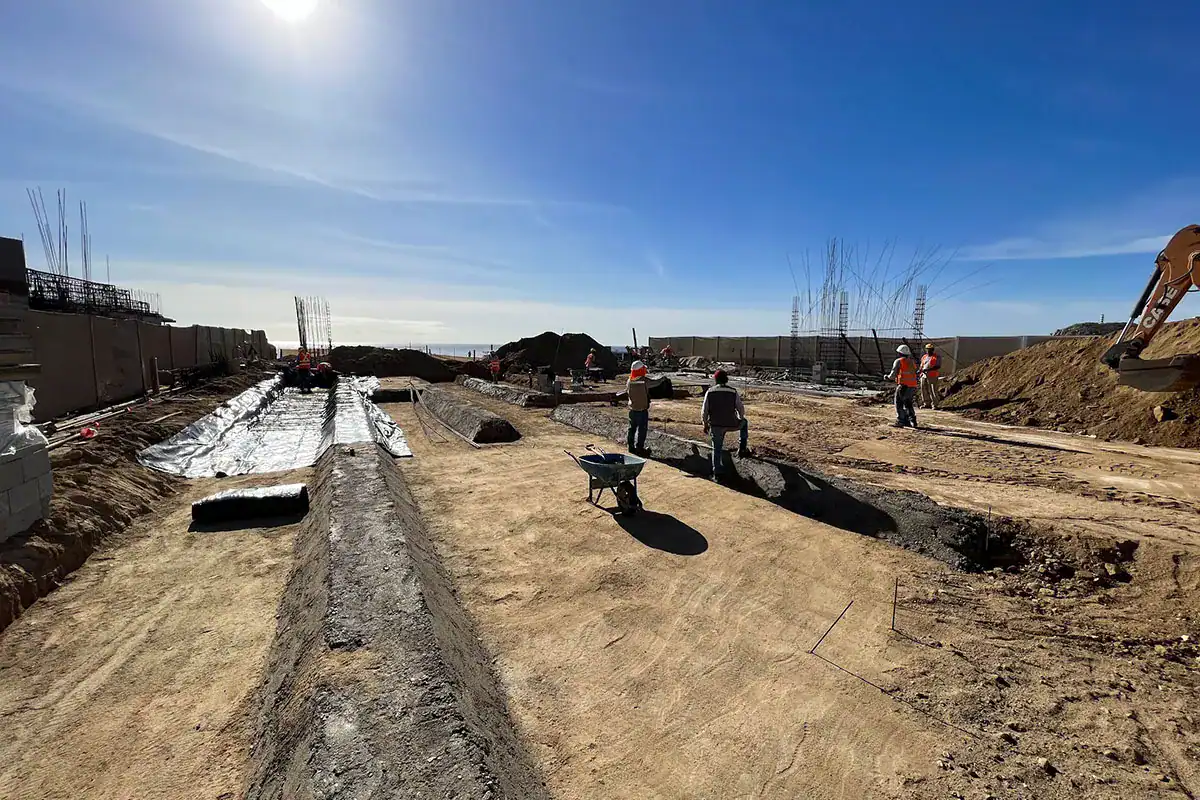 Construction crew working on foundations at a building site near the sea, showing pre-construction in Los Cabos