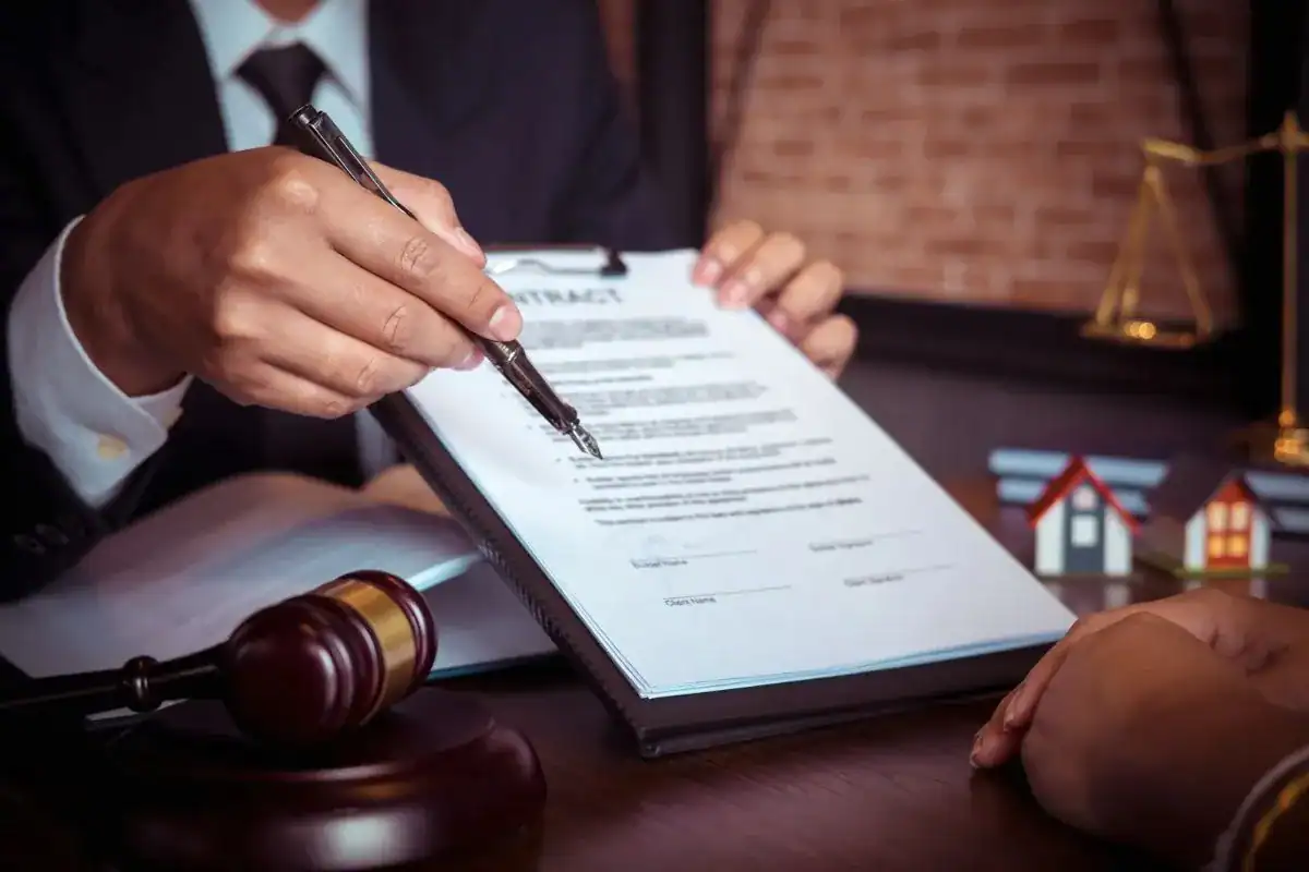 Professional in a suit pointing to a contract with a pen across a desk, on the question of lawyer or notario in Los Cabos
